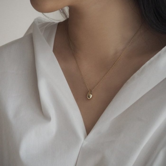 woman's gold silver necklace with tear drop