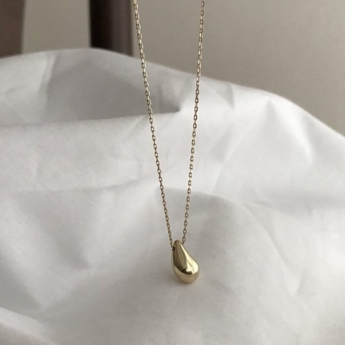 woman's gold silver necklace with tear drop